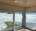 An unfurnished room with large glass sliding doors leading to a snowy outdoor area. The room features a wooden ceiling and tiled floor.