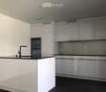 Modern kitchen with white cabinets, black countertops, and stainless steel appliances including a double oven and a sink with a modern faucet.