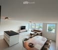 Open-plan living and dining area with a sofa, coffee table, dining table with chairs, and a kitchen island.