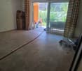 Empty room with tiled floor, large sliding glass door leading to outdoor area, and some stacked boxes in the corner.