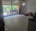 Empty room with tiled floor, large sliding glass door leading to outdoor area, and some scattered items including boxes and shoes.