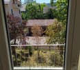Balcony with metal railing overlooking a residential area with houses, trees, and a clear blue sky.