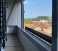 Balcony with a view of a town with red-roofed buildings and distant hills.