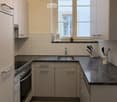 Modern kitchen with light-colored cabinets, granite countertops, stainless steel sink and oven, and various kitchen accessories.