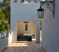 A modern outdoor patio with wooden tiles, a built-in hot tub, and decorative lanterns on the walls.