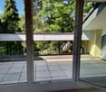 Balcony with tiled floor, metal railing, and view of green trees and neighboring building.