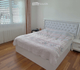 white bed, white nightstands, white curtains, wooden floor, large window