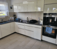 modern kitchen, white cabinets, black countertops, stainless steel appliances, tiled floor