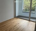 Empty room with light wooden flooring and large glass sliding doors leading to a balcony area.