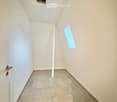 Empty hallway with tiled floor, white walls, a single door on the left, and a small light fixture on the ceiling.