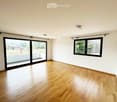 Empty room with wooden flooring, large sliding glass door, and a window with black frame. No furniture or equipment present.