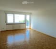 Empty room with wooden parquet flooring, light blue walls, large window, and sliding glass door leading to a balcony.