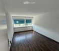 Empty room with wooden flooring, white walls, a window with blinds, and a radiator below the window.
