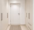 Modern hallway with white walls, built-in cabinets, and a patterned rug on the floor.