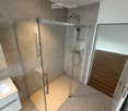 Modern bathroom with a glass-enclosed shower, a white sink, and a sleek faucet.