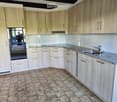 Modern kitchen with light wood cabinets, granite countertop, and stainless steel sink.
