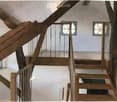 Wooden staircase with metal railing, white walls, and small square windows on the landing.
