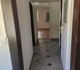 Empty hallway with tiled floor and white walls, featuring several doors and a visible light fixture on the ceiling.
