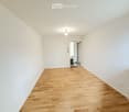 empty room with wooden floor, white walls, ceiling light, power outlet
