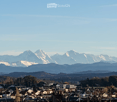 Panoramic view of a town nestled in a valley with snow-capped mountains in the background.