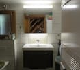 Modern bathroom with a white sink, mirror, and cabinet. Features a bathtub, toilet, and radiator. The mirror has built-in lighting.