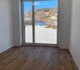Empty room with wooden flooring and large sliding glass doors leading to a snowy outdoor view.