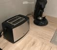 A modern kitchen countertop with a sleek black and silver toaster and a black coffee maker, both placed on a light wooden surface.