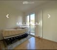 Bright bedroom with wooden flooring, a single bed, a radiator, and a rug. Large sliding glass doors lead to a balcony.