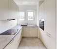 Modern kitchen with white cabinets, a sink, a faucet, an oven, and a countertop.