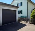 Two-story house with white exterior, green shutters, garage, and wooden fence.
