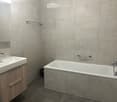 Modern bathroom with a white sink, wooden cabinet, bathtub, and modern fixtures.
