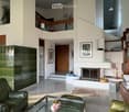 Modern living room with a fireplace, leather sofa, glass coffee table, bookshelf, and decorative items.