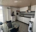 Modern kitchen and dining area with white cabinets, stainless steel appliances, a glass dining table with chairs, and a fan. The space features tiled flooring and large windows with blinds.