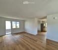 Empty room with wooden flooring, white walls, and a sliding glass door leading to a balcony.