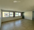 Empty room with tiled floor, large windows, and white walls.
