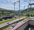 Roof terrace with metal safety railings, overlooking a green valley and scattered houses.