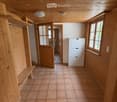 Empty hallway with wooden walls, tiled floor, built-in bench, and open doors leading to other rooms.