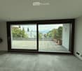 Empty room with large sliding glass doors opening to a tiled balcony, light-colored tiled floor, and recessed ceiling lights.