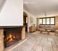 Living room with a stone fireplace, beige sofa, coffee table, armchair, side table, and floor lamp.