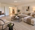 Modern living room with a fireplace, large sectional sofa, coffee table, armchairs, and decorative items.