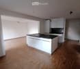 modern kitchen with white cabinets, black countertops, tiled backsplash, wooden flooring, and open layout