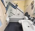 Modern bathroom with a bathtub, toilet, sink, and shower area. Features a geometric tile design on the walls and a sleek, contemporary aesthetic.