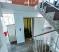 Modern hallway with a staircase leading upwards, white walls, tiled floor, and a partially visible red basket in the background.
