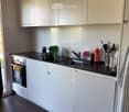 Modern kitchen with white cabinets, black countertop, stainless steel sink, and various appliances and utensils.