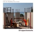 Construction site with workers, rebar, concrete forms, and scaffolding, overlooking a body of water.