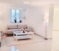 Modern living room with white walls, large windows, grey sofa, coffee table, and floor lamps.