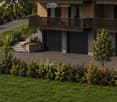Modern two-story building with wooden balconies, garage, and landscaped garden.