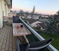 Balcony with wooden table, two chairs, and a view of the neighborhood.