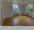 Empty room with wooden flooring, large windows, radiators, and white walls.
