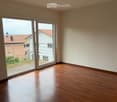 Empty room with wooden flooring and large sliding glass doors leading to a balcony.
